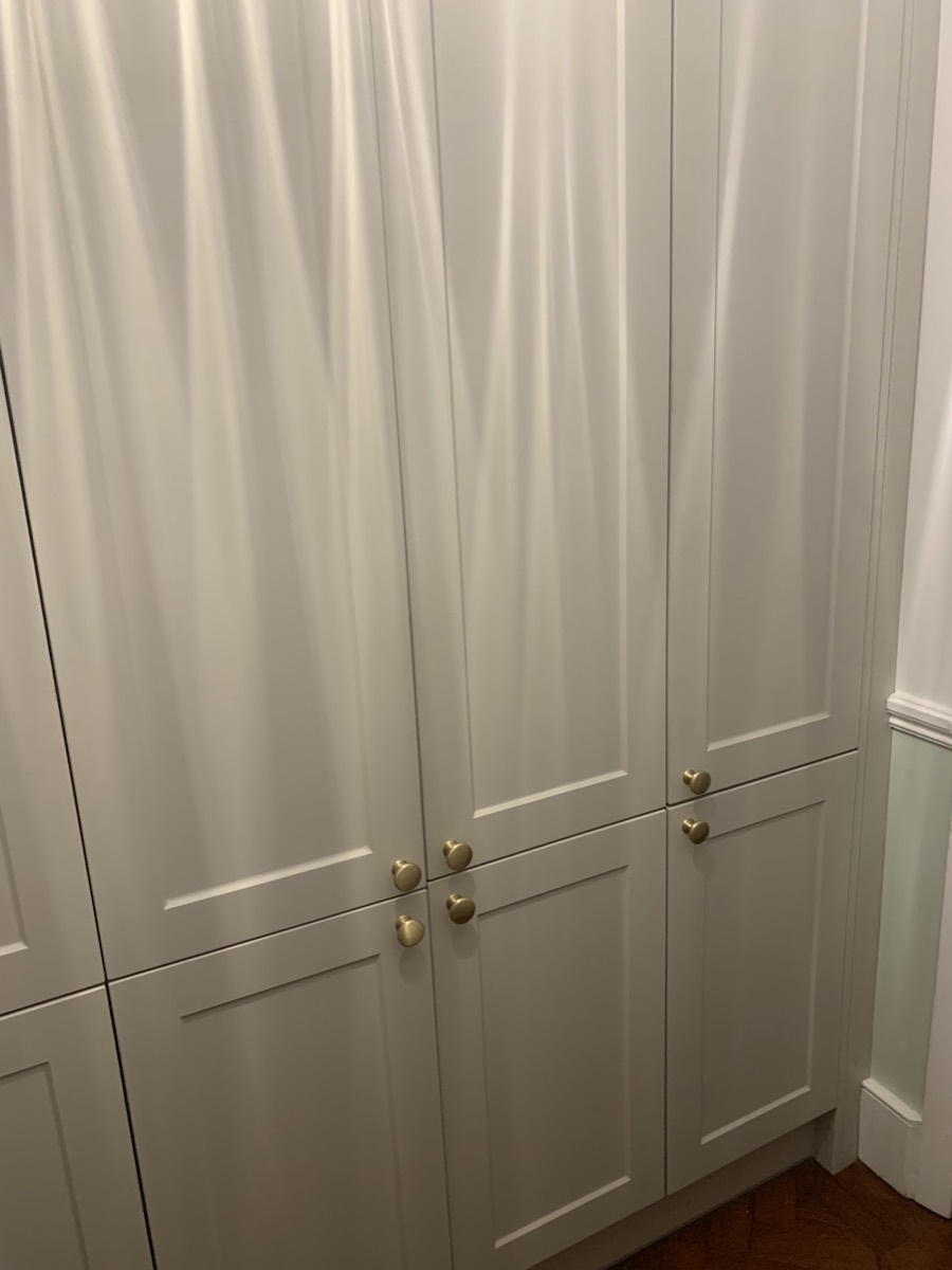 Tall fitted cupboards in cream shaker doors with brass knobs, installed floor to ceiling by Hubbard's Handyman Services.