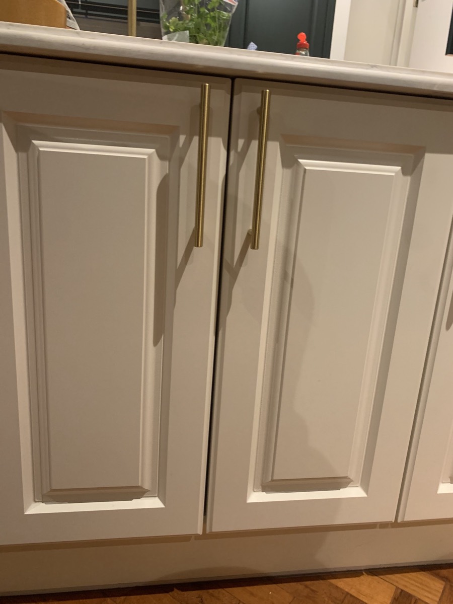 Kitchen base units with cream panelled doors, brass bar handles and a marble worktop, fitted by Hubbard's Handyman Services.